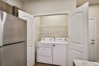 a kitchen with a washer and dryer and a refrigerator at Aventura at Hawk Ridge, Missouri